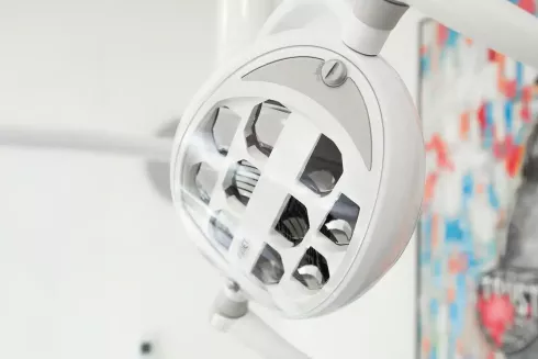 Nahaufnahme einer modernen Behandlungslampe in einer Zahnarztpraxis mit mehreren Spiegelreflektoren für optimale Beleuchtung.